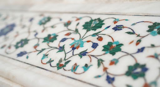 A close-up, highly detailed view of the intricate marble inlay work on the Taj Mahal, Agra. The white marble is pristine, and the floral patterns formed by semi-precious stones are sharp. The lighting is soft and natural, emphasizing the craftsmanship. This small image adds a touch of premium heritage texture to the UI card.